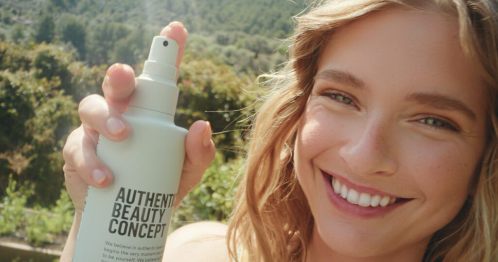 abc Concepts Social Ad: Frau hält Authentic Beauty Concept Sprayflasche in sonniger Natur